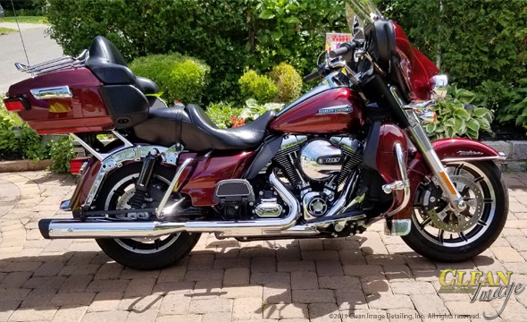 Big red road cruiser Harley Davidson gleaming in the sun.