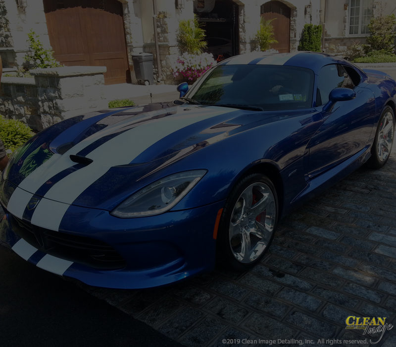 Blue Dodge Viper with white racing stripes after paint correction services.